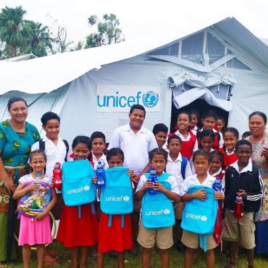 The tent in the background is part of UNICEF's "school in a box", which also contains books, pencils, and even a wind-up solar radio.