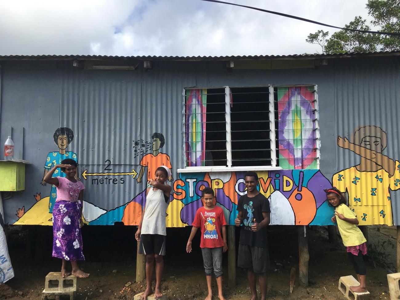 Youth and a COVID-19 awareness mural in Vuniivi settlement Lami, Fiji